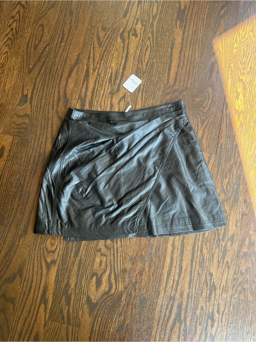 Free People faux leather mini skirt with a draped front detail.
